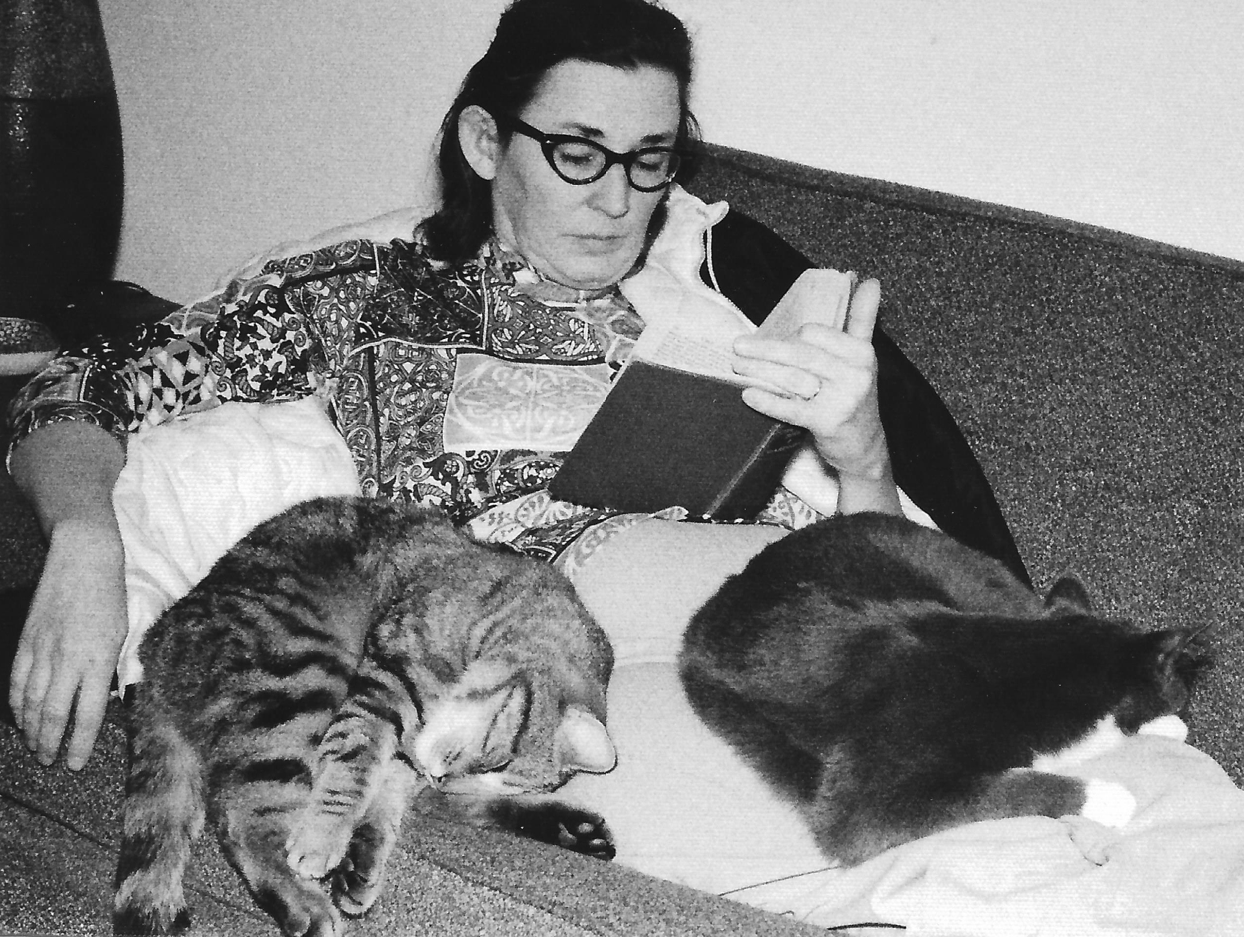 Mom reading with two cats on her lap